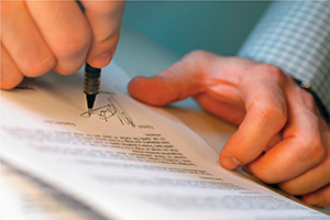 Man's Hands Signing Document --- Image by © Royalty-Free/Corbis